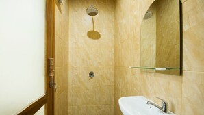 Een badkamer met een douche, een wastafel en een spiegel.