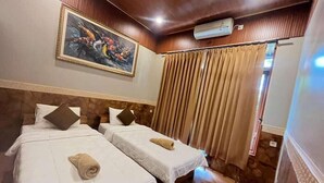 Een hotelkamer met twee bedden, een schilderij aan de muur, een gordijn en een airconditioning.