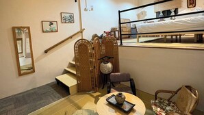 A room with a bed, a small table with a vase, a chair, a sofa, a mirror, and a staircase. - Room-tranquil Retreat in the Heart of Ba (Bangkok)