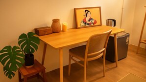 A wooden dining table with a chair, a small potted plant, a candle, a framed artwork, and a refrigerator. - Room-tranquil Retreat in the Heart of Ba (Bangkok)