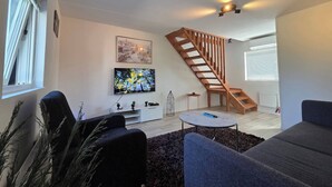 Un soggiorno moderno con una scala, una TV a schermo piatto e un'accogliente zona salotto.