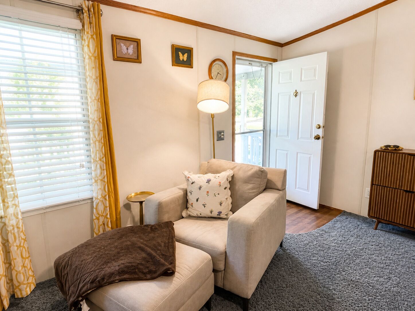 Un salon chaleureux avec un canapé beige, un plaid marron et une lampe.