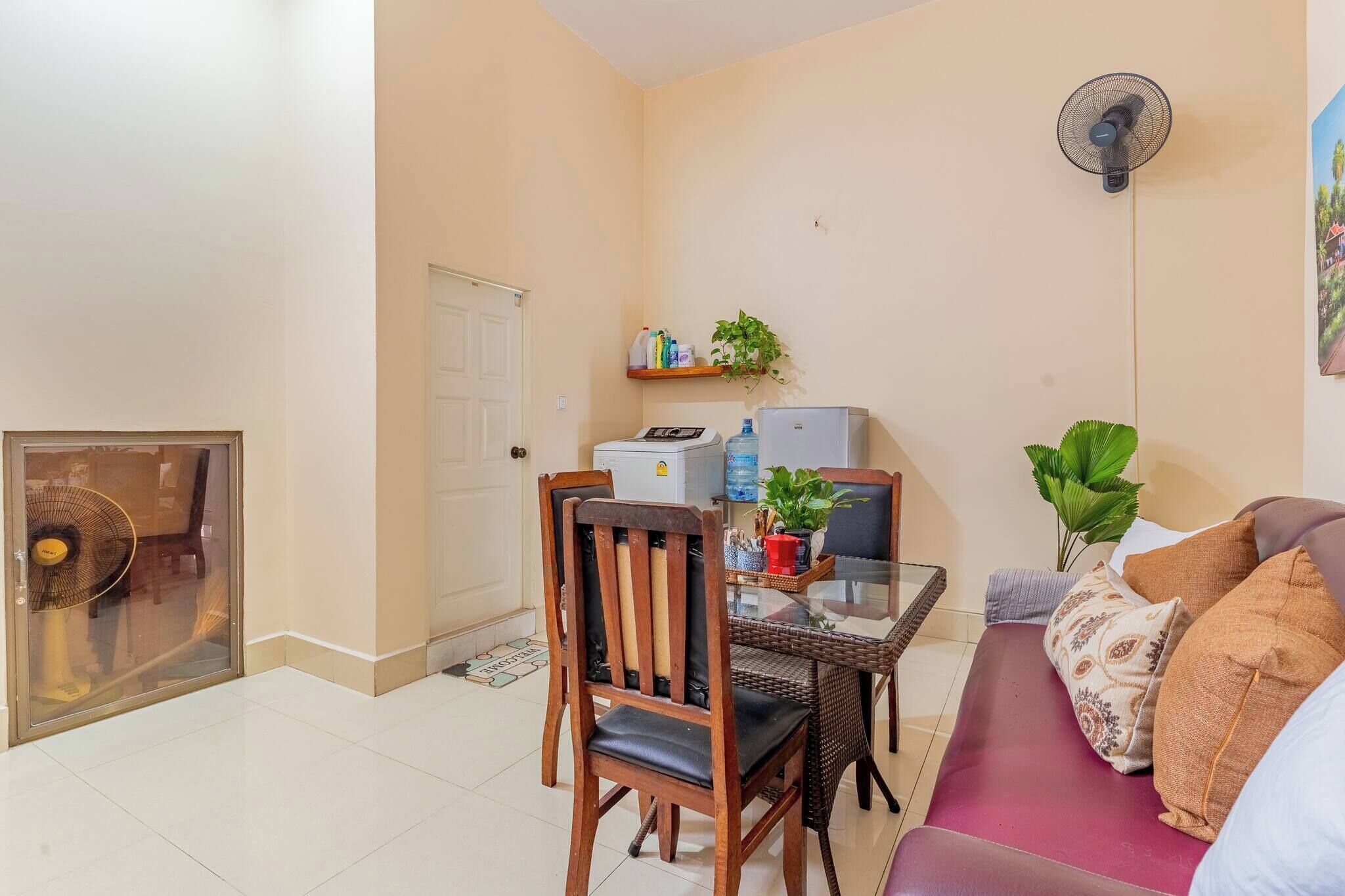 Un espacio habitable compacto con una mesa de comedor, un sofá, un ventilador y un refrigerador.