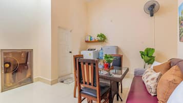 Un espacio habitable compacto con una mesa de comedor, un sofá, un ventilador y un refrigerador.