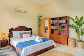 A neatly arranged bedroom with a bed, bedside lamp, wardrobe, and potted plants. - Sovann Haven - 2 Bedroom Retreat in Bassac Lane (Phnom Penh)