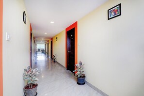 Un pasillo con piso de baldosas, plantas en macetas y una puerta con el símbolo del número.