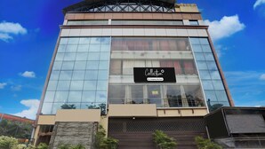 Un edificio moderno con una amplia fachada de vidrio, un cartel llamativo y una escalera que conduce a la entrada.