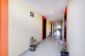 A hotel corridor with doors, potted plants, and a light switch on the wall. - Collection O Summanahalli Bus Stand (Bangalore)