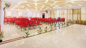 Un salón amplio con filas de sillas rojas, un diseño de techo moderno y un suelo pulido.