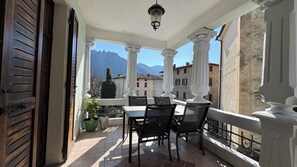 Un balcone con tavolo e sedie, una lampada a sospensione e vista sulle montagne.