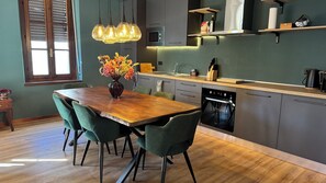 Una cucina moderna con un tavolo da pranzo in legno, sedie verdi e illuminazione a sospensione.