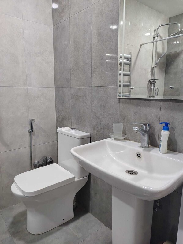 A bathroom with a toilet, sink, and shower.