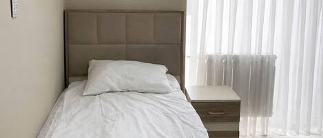 A minimalist bedroom with a single bed, a bedside table, and an air conditioning unit.