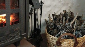 A fireplace with logs, a woven basket with branches, and a stone wall.