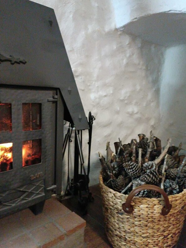 A fireplace with logs, a woven basket with branches, and a stone wall.
