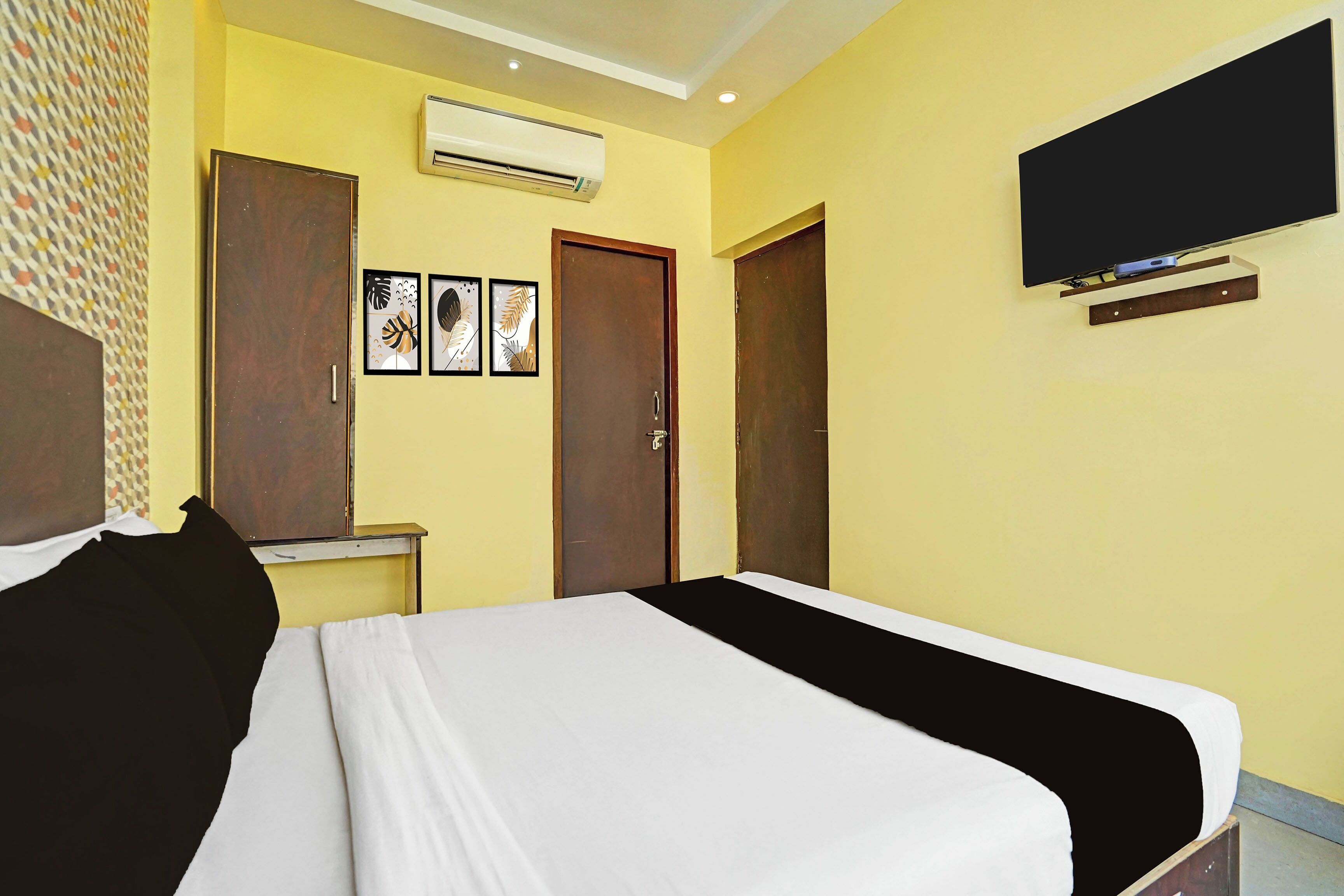 Une chambre d’hôtel avec un lit, un téléviseur fixé au mur et une porte.