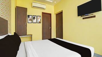 Une chambre d’hôtel avec un lit, un téléviseur fixé au mur et une porte.