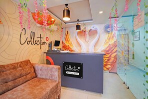 A hotel reception area with a sofa, a reception desk, and a wall with a 'Collection' sign. - Super Collection O Prayagraj Bus Stop (Prayagraj)