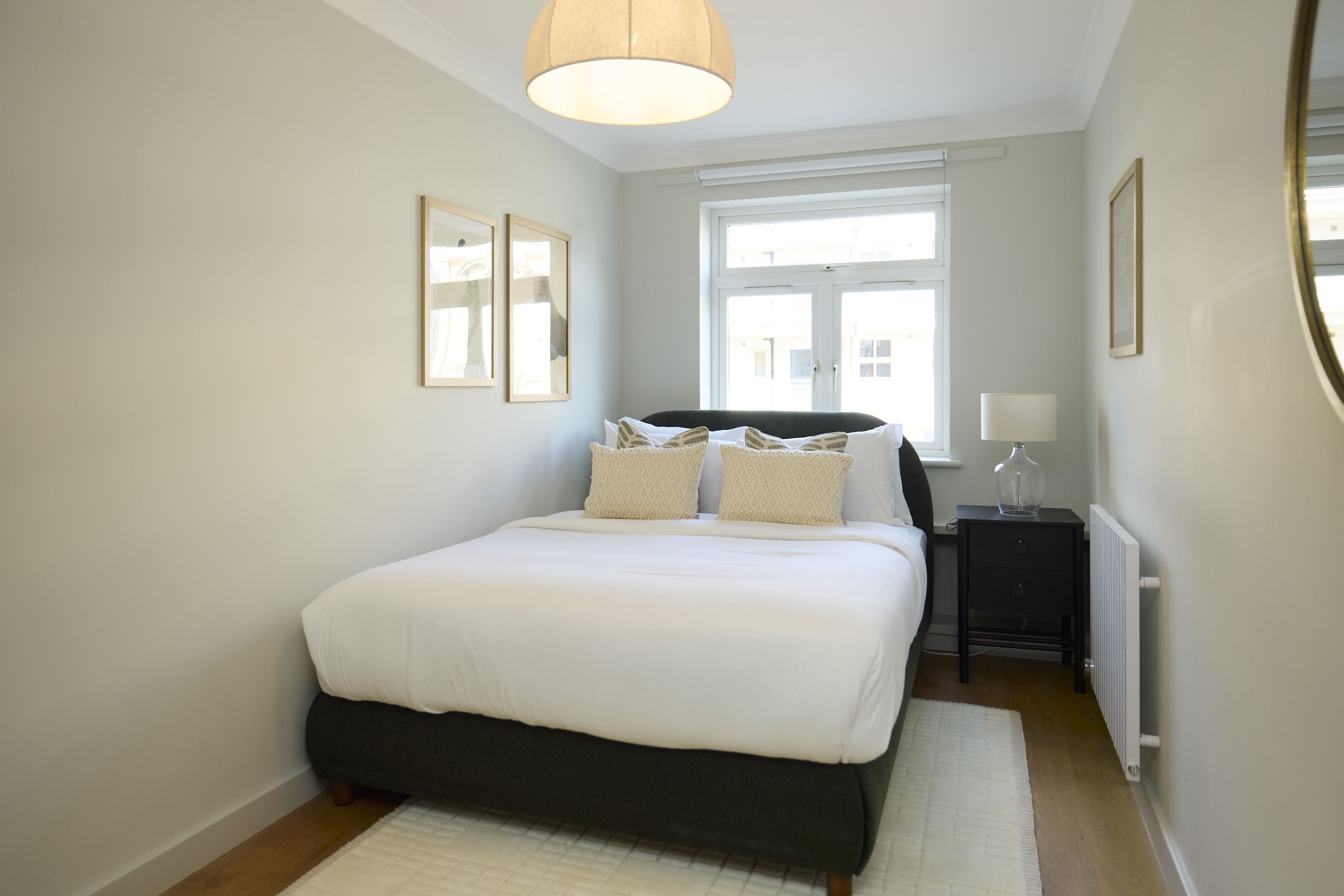 A bedroom with a bed, bedside tables, a window, and a radiator.