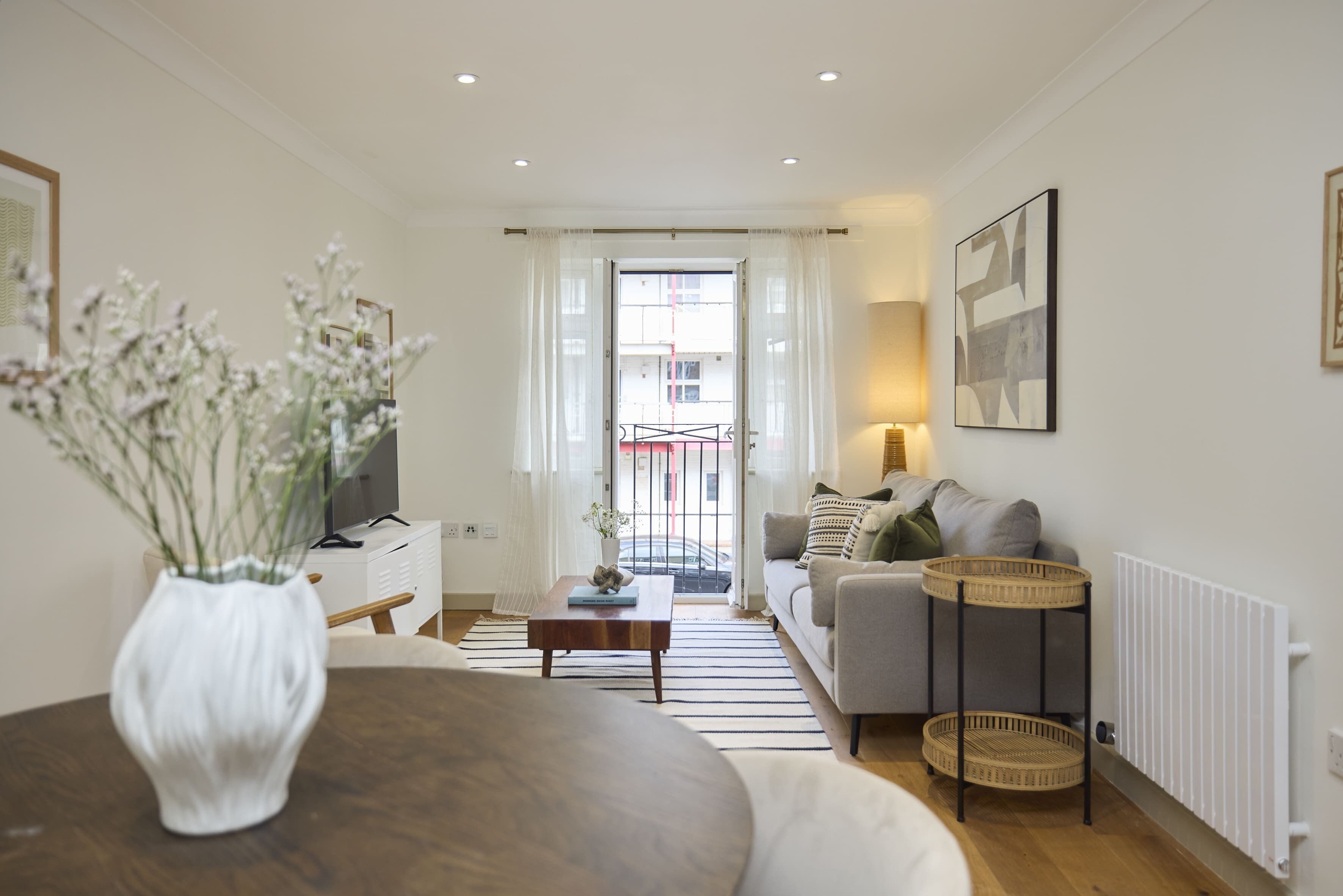 A modern living room with a sofa, a coffee table, a TV, and a dining area with a table and chairs.