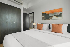 Ein Hotelzimmer mit einem großen Bett, einem dunklen Kleiderschrank und einem Bild an der Wand.