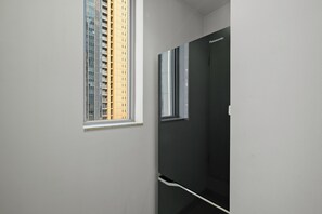 Ein schmaler Korridor mit einem Fenster links und einer Tür rechts.