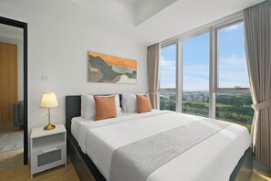 A modern hotel room with a large bed, a bedside table with a lamp, a painting on the wall, and a view of the city through large windows. - Korava by Kozystay - BSD (Tangerang)