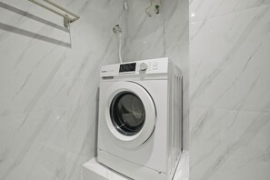 Eine Waschmaschine mit Frontlader in einem Badezimmer mit Marmorwand.