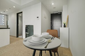 Eine moderne Küche mit weißen Schränken, einem integrierten Kühlschrank und einem Essbereich mit einem runden Tisch für zwei Personen.