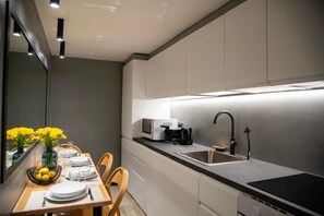 A modern kitchen with a dining area, equipped with a sink, stove, and a coffee maker. - House Domusella Apartment, in the heart of Rome—quiet and comfortable (Roma)
