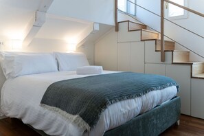 Un dormitorio con cama, una escalera y una ventana.