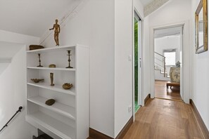 A hallway with a staircase, a white wall, and a wooden floor. - Elegance and comfort in the heart of Venice – Canal view in Dorsoduro (Venice)