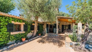 A courtyard with a stone wall, potted plants, and a pergola. - Villa Near Pollensa Old Town (Pollença)