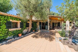 A courtyard with a stone wall, potted plants, and a pergola. - Villa Near Pollensa Old Town (Pollença)