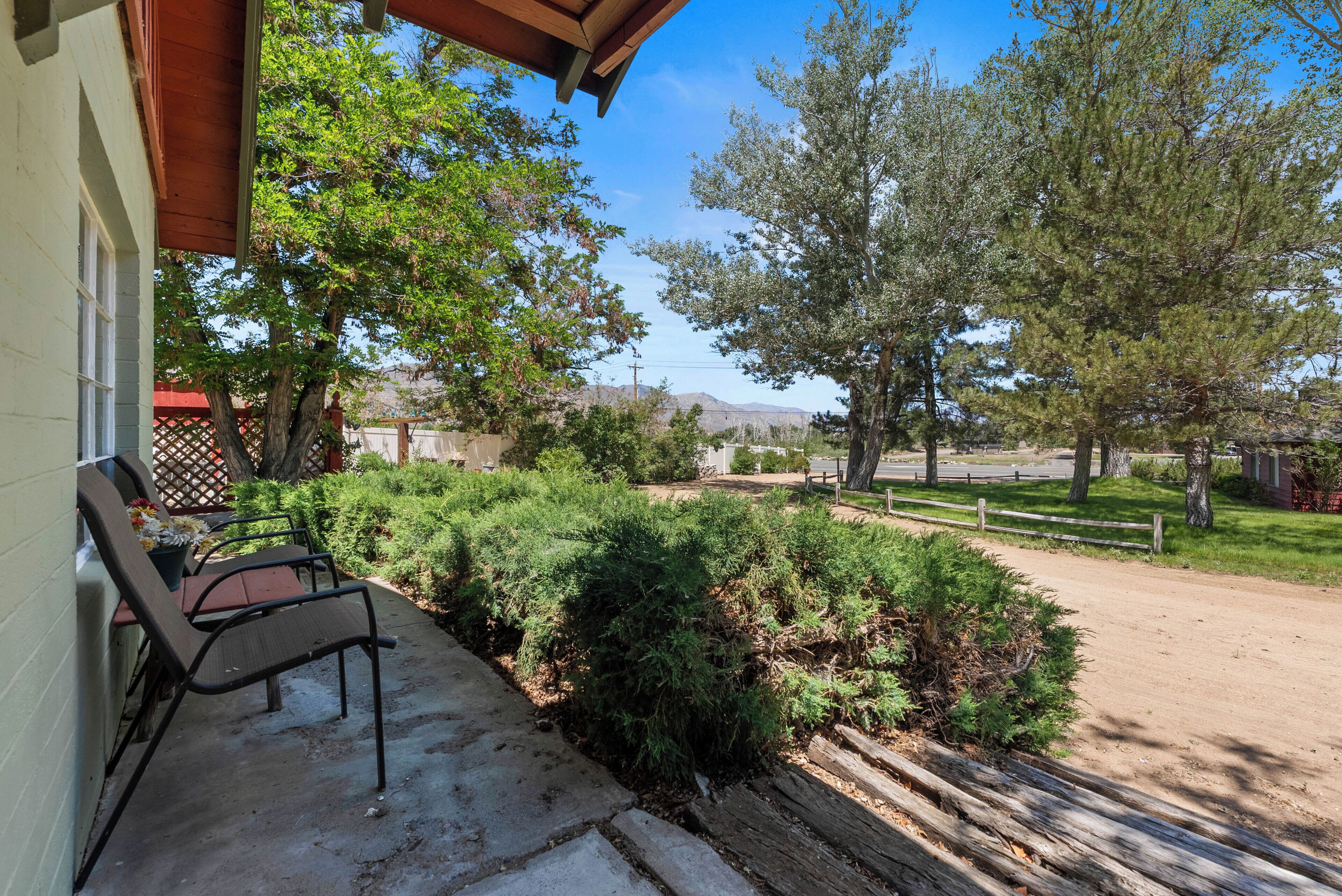 A patio with outdoor furniture, a wooden fence, and a view of trees and hills.