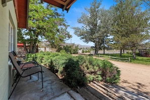 Un patio con mobiliario exterior, una valla de madera y vistas a árboles y colinas.
