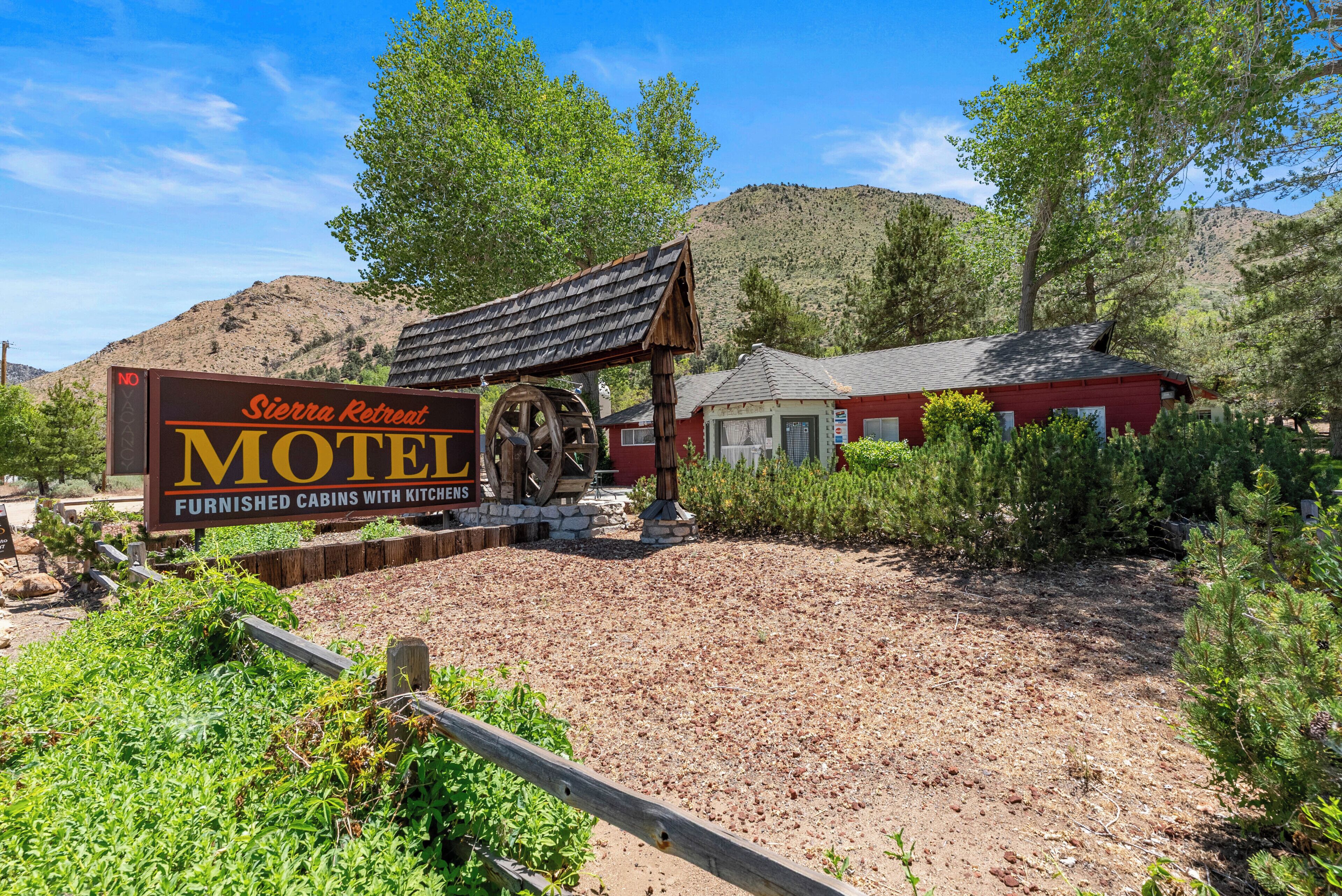 A Sierra Retreat Motel sign with a wooden structure and a red building in the background.
