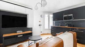 A modern kitchen with dark cabinetry, a built-in oven, and a coffee maker. - Cozy Apartment 1br/4p - La Villette (Paris)