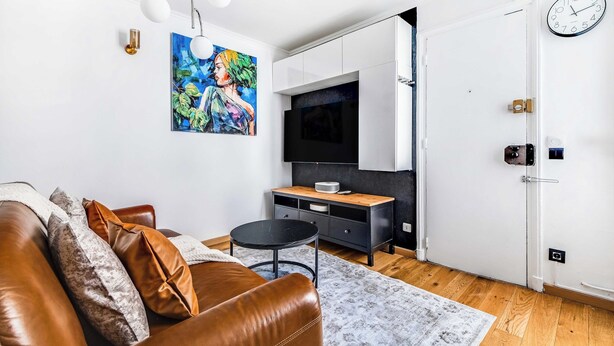 A modern living room with a leather sofa, a coffee table, and a painting on the wall. - Cozy Apartment 1br/4p - La Villette (Paris)