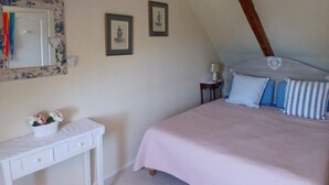 Un dormitorio con una cama, una mesita de noche, un aparador, un espejo y dos cuadros en la pared.