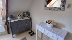 Un dormitorio con un aparador gris, una mesita de noche blanca, un espejo y un par de mancuernas en el suelo.