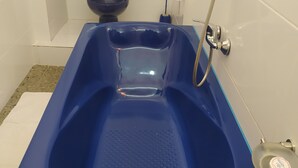 A bathroom with a blue bathtub, a toilet, and a shower. - ivotel  (Antananarivo)