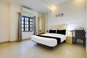 Une chambre d’hôtel avec un lit, une table de chevet, une chaise et une fenêtre avec des rideaux.