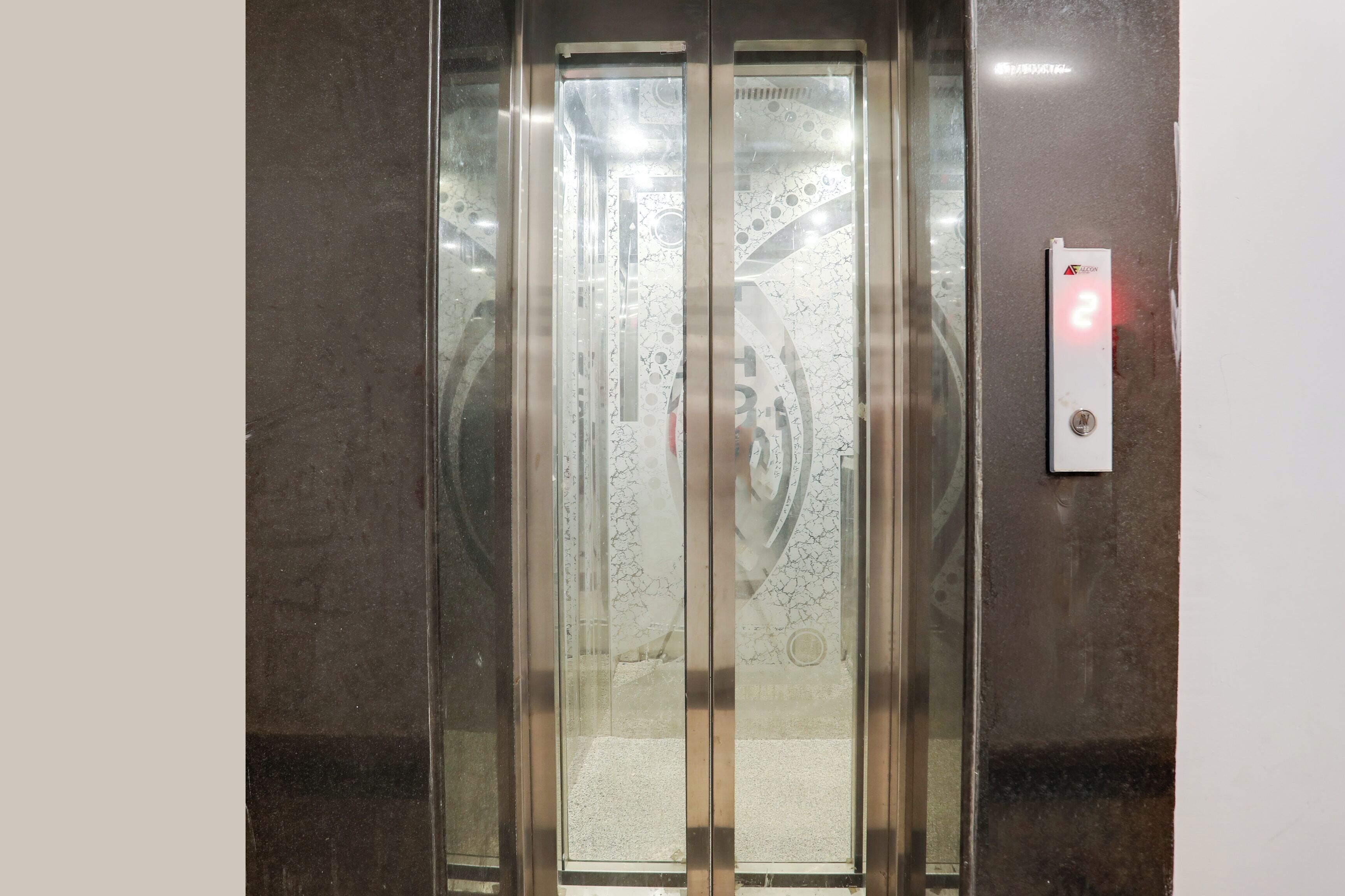 Un ascensor con pared de mármol y panel de control con una luz roja.