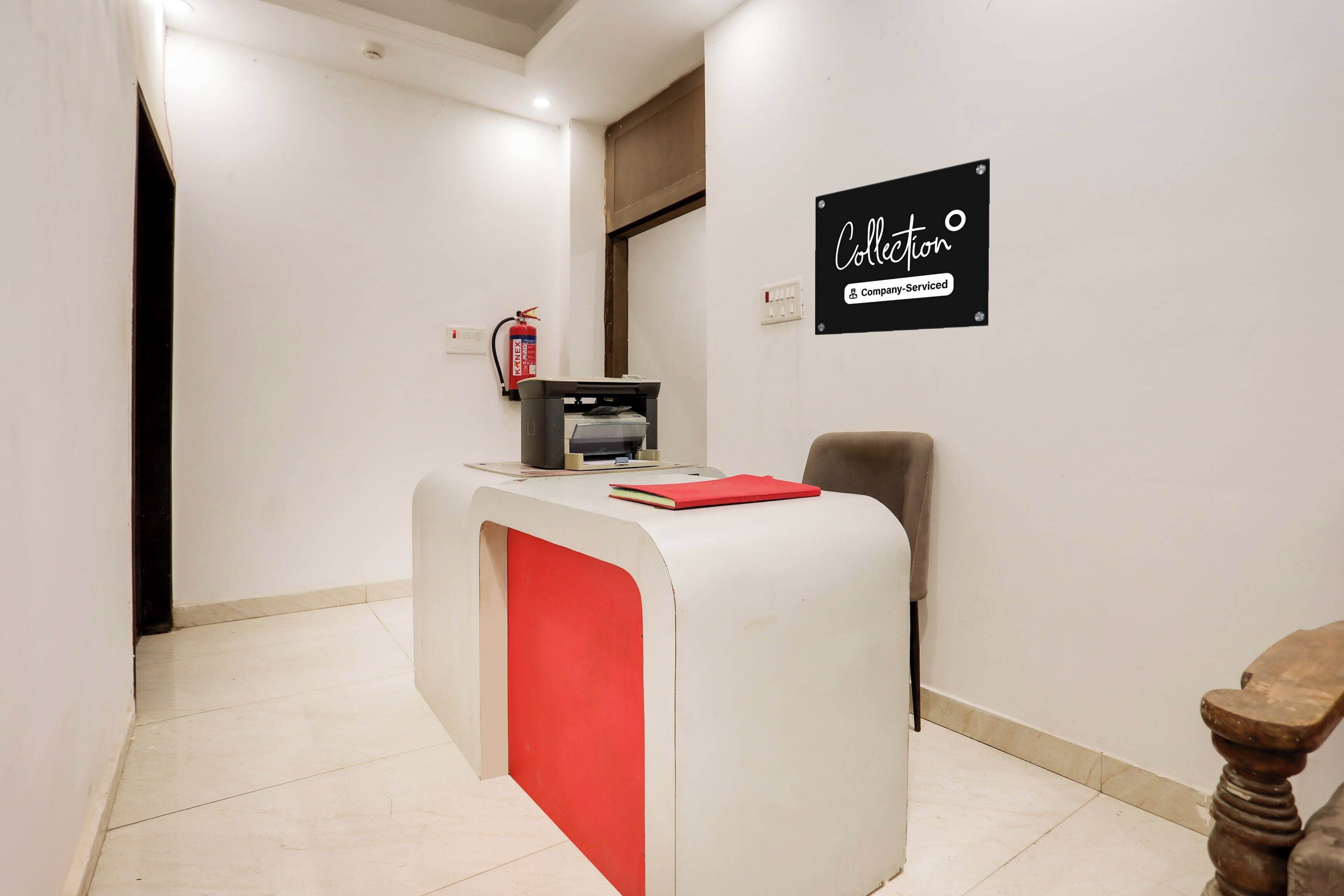 A reception desk with a red accent, a fire extinguisher, and a sign indicating company-serviced services.