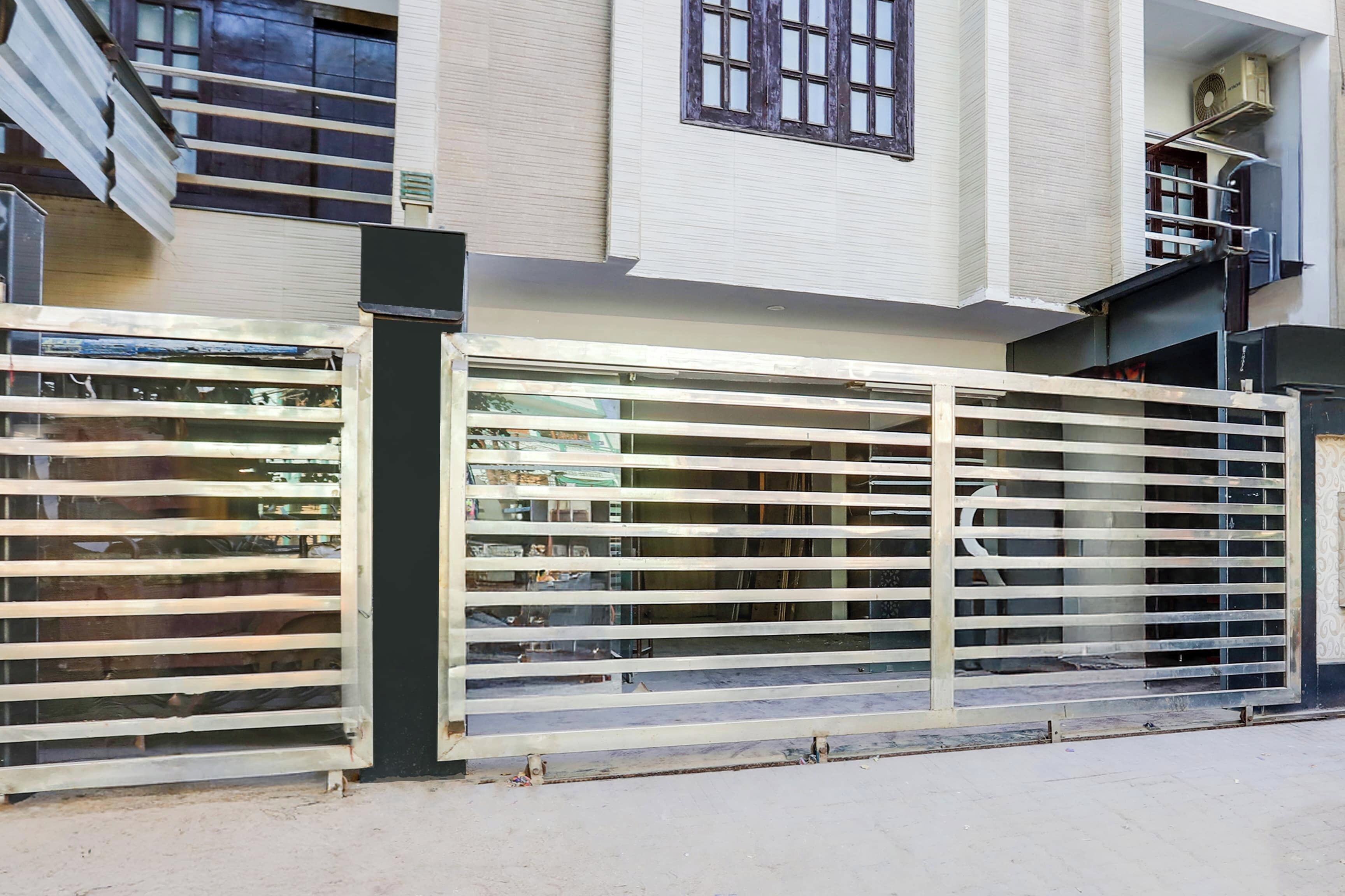 A gated entrance with a metal fence and a staircase leading to a building with a white facade and windows.