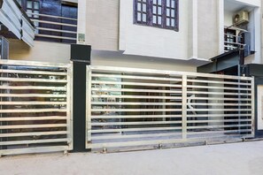 Una entrada tancada amb una tanca de metall i una escala que condueix a un edifici de façana blanca i finestres.