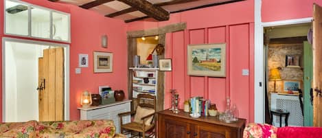 A cozy room with a wooden ceiling, a floral sofa, a wooden cabinet, and a bookshelf.