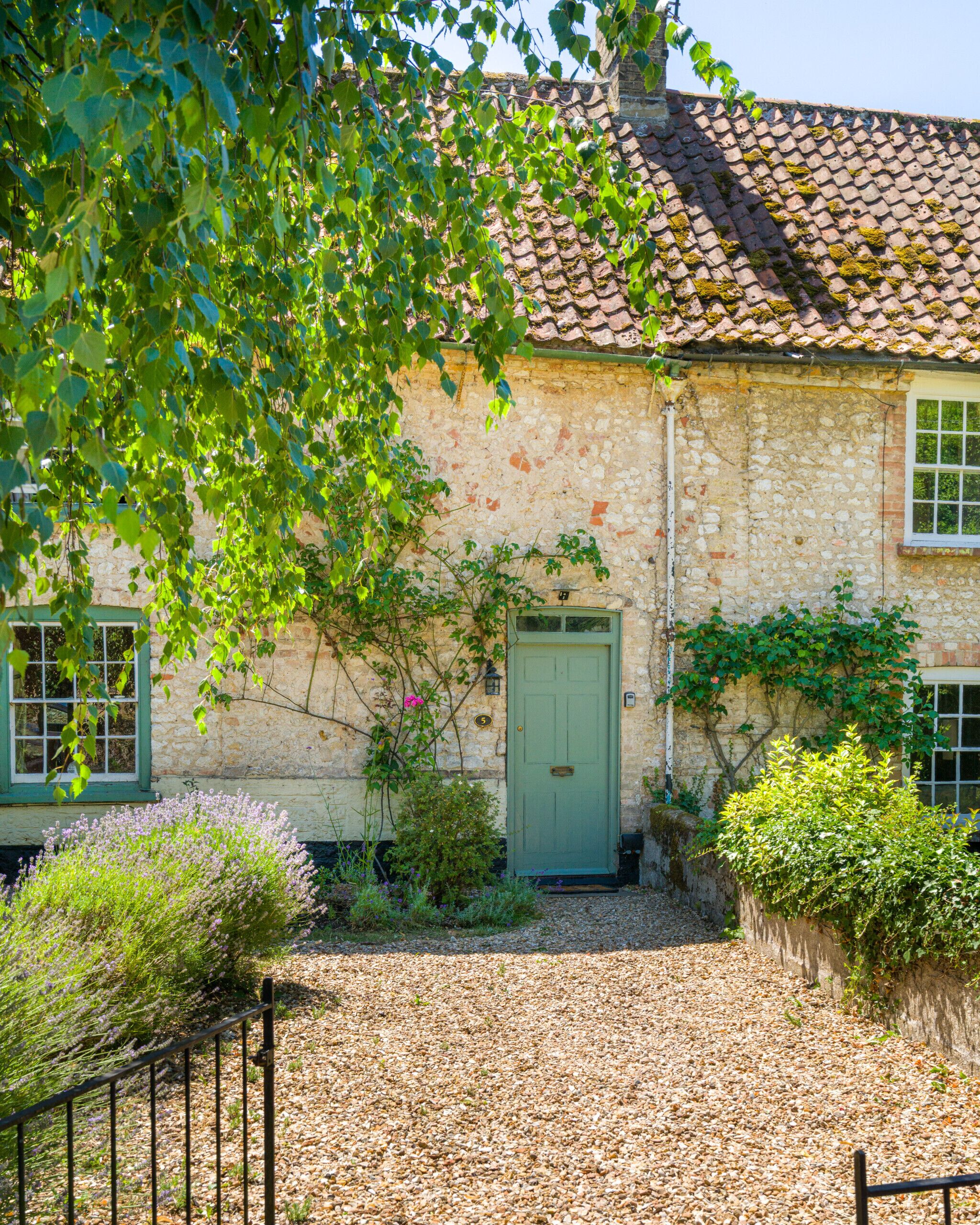 A stone building with a green door, a window with a white frame, and a tiled roof.