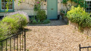 A stone building with a green door, a window with a white frame, and a tiled roof. - Finest Retreats | Lavender Cottage (Methwold)